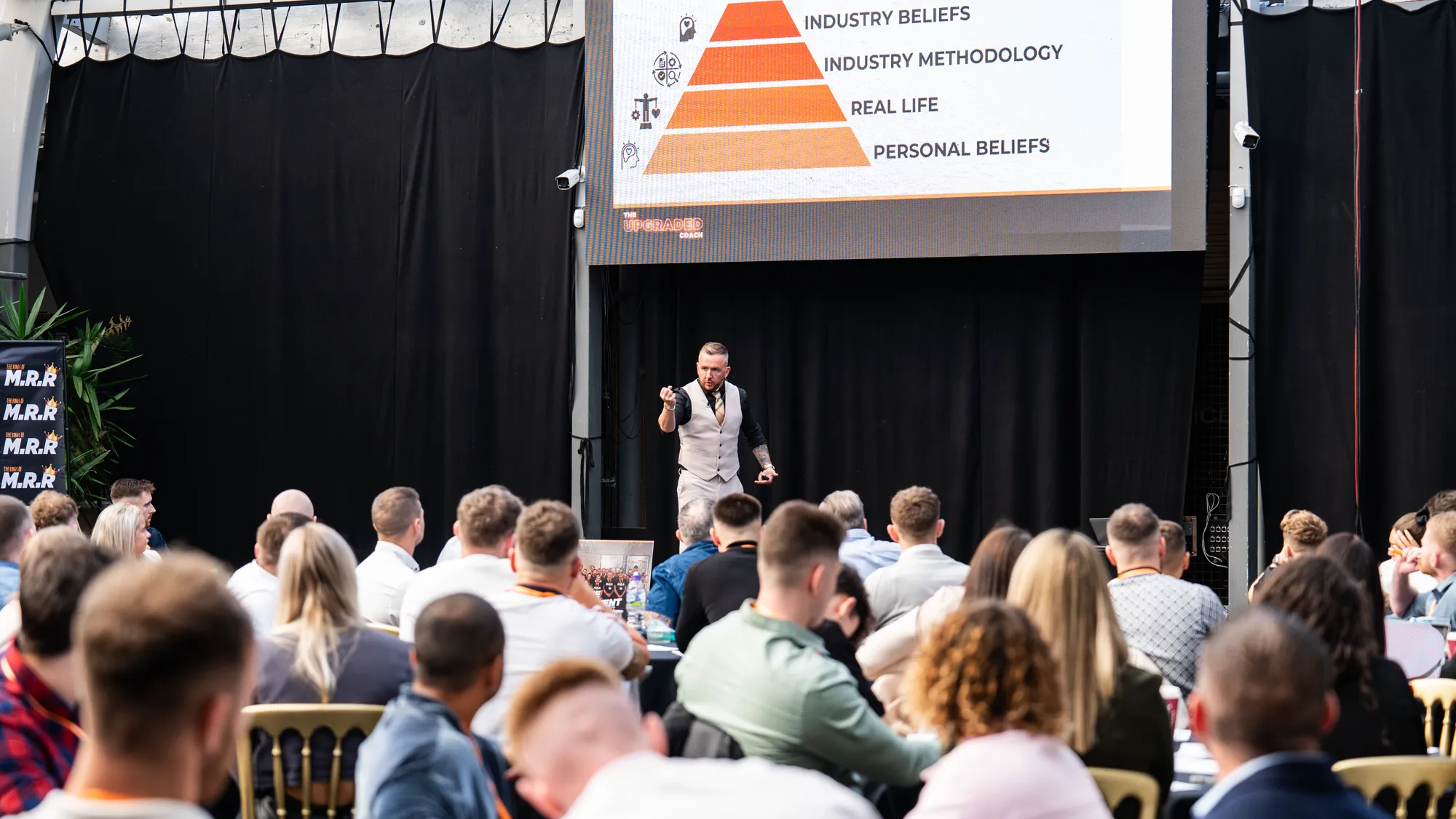 A room of business owners at an MRR Agency event, hands raised.